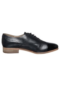 Chaussure noire en cuir à lacets avec embout brillant, talon bas empilé et texture lisse. Présente des coutures détaillées sur les côtés.