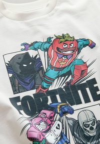 Short-sleeve white T-shirt featuring a colorful graphic print of cartoon characters from Fortnite, including a tomato, skeleton, and robot.