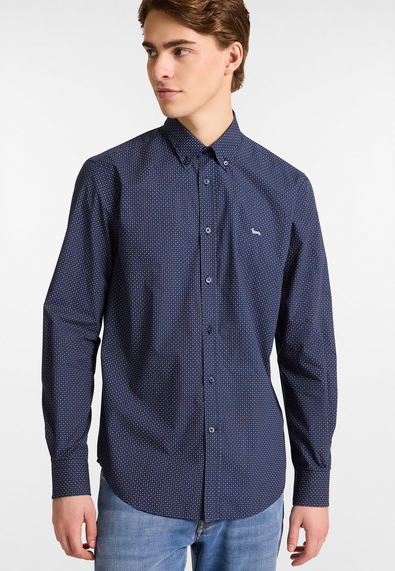 Camicia blu navy a maniche lunghe con un piccolo motivo geometrico, colletto a bottoni e logo ricamato sul petto. Tessuto in cotone, texture liscia.