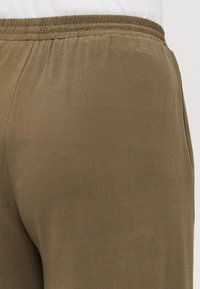 Olive green pants with an elastic waistband, featuring a smooth texture and subtle geometric pattern. No visible pockets.