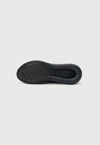 Black rubber sneaker sole with a textured pattern, featuring ridges and grooves for traction. Smooth inner area with a rounded shape.