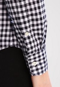 Camicia a quadri bianca e nera con polsini con bottoni, vestibilità slim e tessuto leggero con dettagli di cucitura a vista.