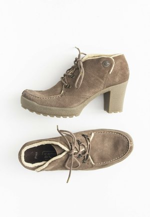 Bottes chelsea en daim marron à lacets avec talons blocs et doublure en polaire, vues de côté et de dessus sur fond blanc.