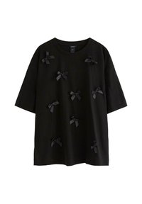 Sort kortærmet T-shirt med rund hals, dekoreret med flere små sorte satinbuer spredt over forsiden.