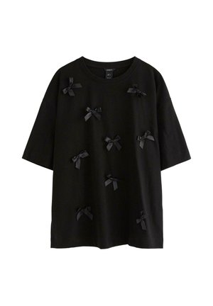Svart t-shirt med kort ärm och rund halsringning, dekorerad med flera små svarta satängrosetter utspridda över framsidan.