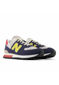 Baskets bleu marine et grises avec des accents jaunes, en mesh et daim, semelle plate noire, col rembourré et languette de talon rouge.