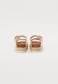 Béžové espadrilkové sandály s platformou, které mají tkanou juta střední podrážku a zaoblený design vzadu, zdobené dekorativní mašlí.