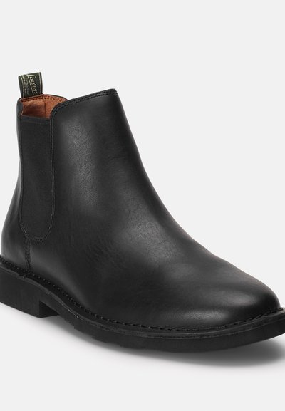 Bota chelsea de cuero negro con un acabado suave, paneles laterales elásticos y un tirador en el talón. Suela texturizada para agarre y durabilidad.