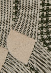 Calze lavorate a maglia con un design a righe in beige e verde scuro, con una finitura testurizzata. Accentuate da una costola decorata e da una zona delle punte con motivo.