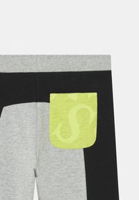 Grijze en zwarte joggingsbroeken met een textuur van een lichtgroene patchzak met een subtiel logo patroon. Elastische tailleband, casual ontwerp.