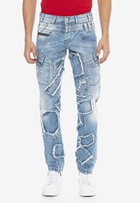 Hellblaue Jeans mit starkem Used-Look und großen Rissen, schmaler Passform, mehreren Taschen und einem ausgewaschenen Finish. Verfügt über eine Reißverschlusstasche auf der Vorderseite.