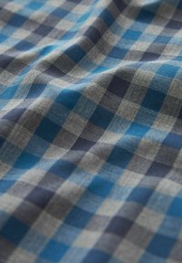 Tela de algodón tejida con un patrón a cuadros en azul y gris, con cuadrados de tamaño mediano, textura suave y caída ligera.