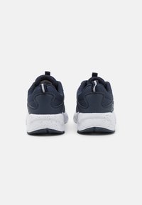 Baskets de sport bleu marine avec une tige en tissu texturé, semelle à éclats blancs et une languette au talon pour un enfilage facile. Design à talon pour un soutien.