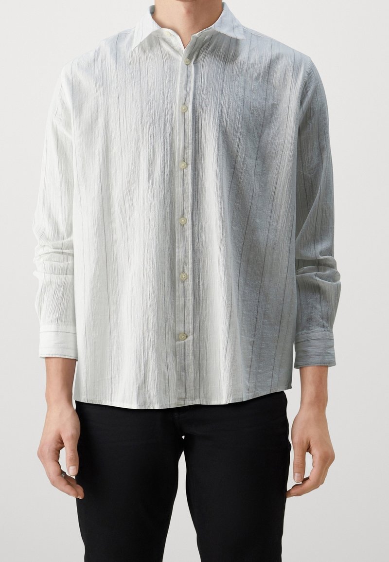 Camisa de botón gris claro con una tela texturizada, que presenta un cuello extendido, mangas largas y sutiles rayas verticales.