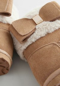 Brązowe zamszowe botki za kostkę z puszystym sztucznym futrem i dekoracyjną kokardą. Posiadają metalową metkę z wytłoczonym napisem "BAKER".