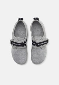 Grå stoff slip-on sko med en svart stropp merket "LIVING KITZBÜHEL." Rundt design, myk tekstur og lukket tå.