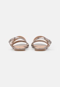 Metalliska silversandaler med platta sulor, tunna remmar och spänne. Slät läderöverdel, platt sula och öppen bakkonstruktion.