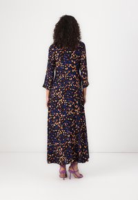 Maxi dress with a black base and vibrant orange and blue leaf pattern, featuring long sleeves and a flowing silhouette.