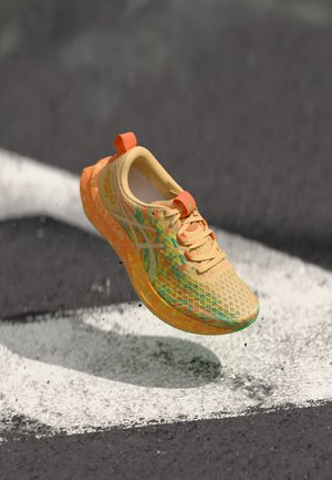 Chaussure de course légère jaune avec motifs colorés, tige en mesh et semelle texturée. Comprend une languette de talon orange et des lacets.