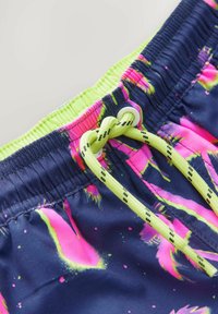 Navy simbyxor med neongröna och rosa tropiska mönster, med elastisk midja och dragsnöre med svarta accenter. Lätt material.