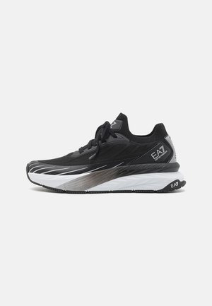 Schwarz-weiße Sportschuhe mit einem eleganten Design, einem strukturierten Obermaterial und einer geschwungenen, geschichteten Sohle. Mit Logo an der Seite.