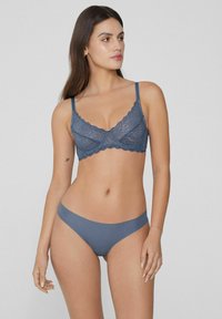 Krajkový bralet v tmavě modré barvě s nastavovacími ramínky a vlnitými okraji, spárovaný s odpovídajícími jednobarevnými tmavě modrými kalhotkami. Hladká textura.