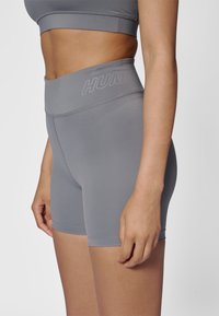 Shorts d'entraînement gris en mat ériau lisse et extensible avec une taille haute, présentant un logo discret et des détails de couture.