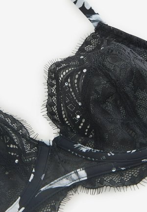 Svart spetsbehå med blommigt mönster på banden, smyckad med små strasstenar och en texturerad finish längs kanterna.