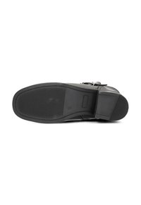Semelle en cuir noir avec une texture antidérapante, forme plate, bout arrondi et détails de couture subtils. Fini lisse avec des accents matériels minimaux.