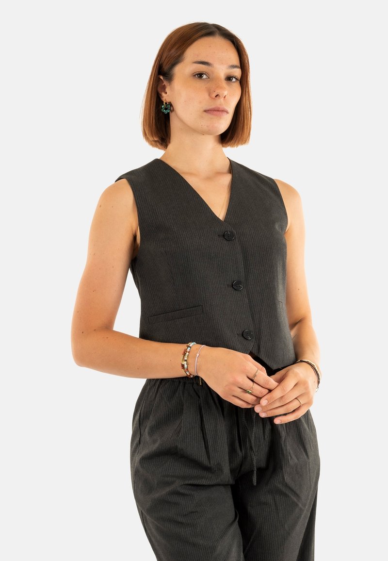 Gilet senza maniche grigio scuro con scollatura a V profonda, tre bottoni e una tasca frontale. Il tessuto strutturato ha righe verticali.