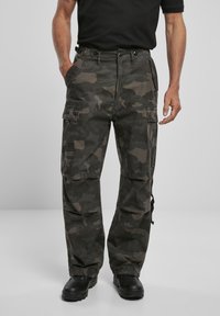 Pantalones cargo en un patrón de camuflaje oscuro, fabricados con tela duradera. Con múltiples bolsillos, un corte holgado y puños en los tobillos ajustables.
