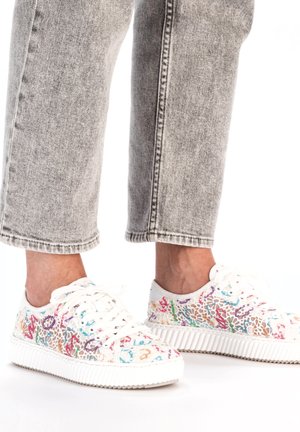 Baskets blanches à lacets ornées d'un motif floral coloré. La tige texturée contraste avec une semelle blanche épaisse et des lacets plats.