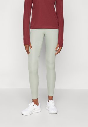 Lysegrønne leggings laget av stretchy materiale, sammen med en burgunder langermet topp. Hvite joggesko fullfører antrekket.