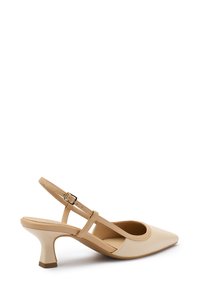 Scarpa slingback in pelle lucida color nude con punta affusolata, tacco medio e cinturini incrociati dotati di una piccola fibbia regolabile.