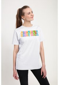 Hvid bomulds-T-shirt med farverige tegneseriebjørne-designs og teksten "Original Care Bears" i fed, legende skrift. Korte ærmer.