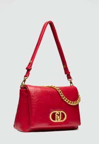 Sac à main en cuir rouge à la forme structurée, avec un accent en chaîne dorée, une texture embossée et un logo en métal à l'avant.