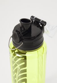 Groene plastic waterfles met een zwart deksel, uitgerust met een flip-top tuit, een vergrendelmechanisme en een metalen draaghandgreep voor draagbaarheid.