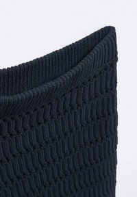 Cesto per riporre lavorato a maglia in blu scuro, caratterizzato da un motivo texture con linee a zigzag, materiale morbido e un bordo superiore leggermente arrotolato.