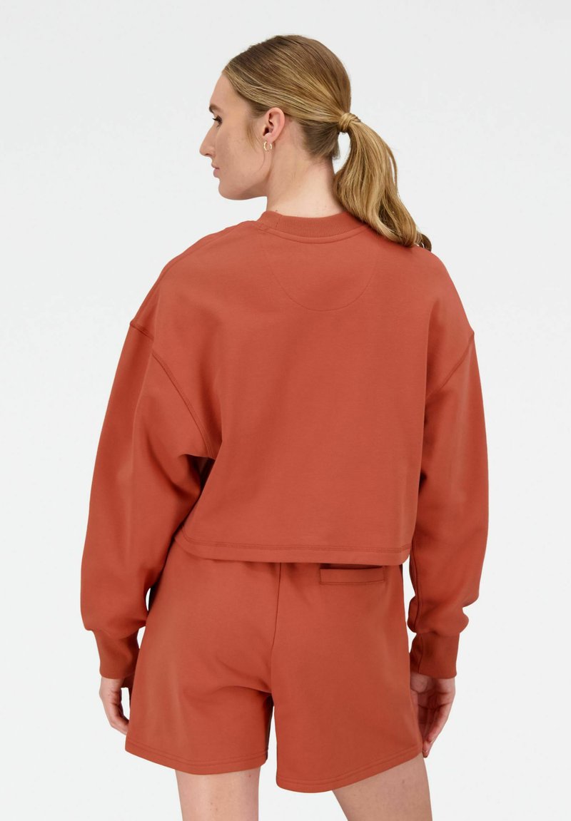 Roestkleurige cropped sweatshirt met lange mouwen, gecombineerd met bijpassende shorts. Gladde textuur, relaxte pasvorm en minimalistisch ontwerp.