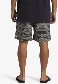 Mönstrade badshorts med svart och gräddfärgad diamantdesign, tillverkade av lättviktig tyg. Bärs med svarta flip-flop-sandaler och har en lös passform.