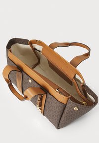 Borsa a tracolla con motivo marrone, dettagli e manici in pelle beige. L'interno presenta un compartimento con cerniera e rivestimento in tela. Sono incluse fasce regolabili.