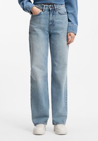 Jeans de mezclilla azul claro de cintura alta con corte recto, con cierre de botones, trabillas para cinturón y textura desgastada.