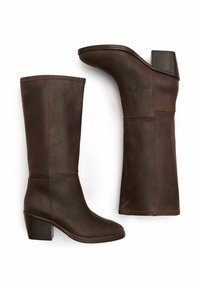 Botas de cuero marrón hasta la rodilla con punta redonda, tacón apilado y costuras en contraste; textura suave con detalles de diseño mínimos.