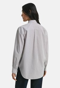 Button-up shirt van lichtgestreept katoen. Beschikt over een klassieke kraag, lange mouwen en een afgeronde zoom. Subtiele witte en blauwe strepen.
