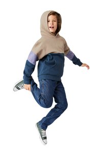 Huppari vaaleassa, tummansinisessä ja laventelin värisessä väri-blockissa, jossa on kengurutasku. Yhdistettynä sinisiin farkkuihin ja vihreisiin lenkkareihin.