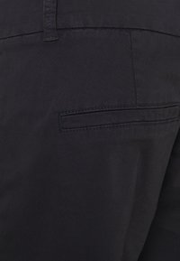 Pantaloni blu navy realizzati in un tessuto leggero e morbido, con una piccola tasca posteriore discreta e un dettaglio di cucitura sofisticato.