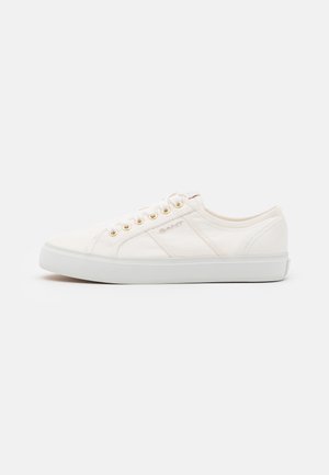 Weißer Low-Top-Canvas-Sneaker mit goldenen Ösen, weißer Sohle und dezentem Branding an der Seite, auf neutralem Hintergrund gezeigt.