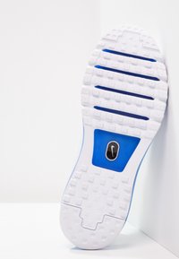 Vit gummisul med ett texturerat mönster, med blå accenter och en liten svart logotyp. Designen inkluderar spår för grepp.