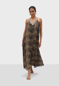 Robe maxi en imprimé léopard avec un décolleté en V profond, en tissu léger et avec une silhouette fluide. Présente un ornement décoratif au niveau du décolleté.