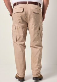 Pantalones cargo beige con dos bolsillos traseros y bolsillos laterales, fabricados en una tela ligera, con piernas rectas y un dobladillo vuelto.